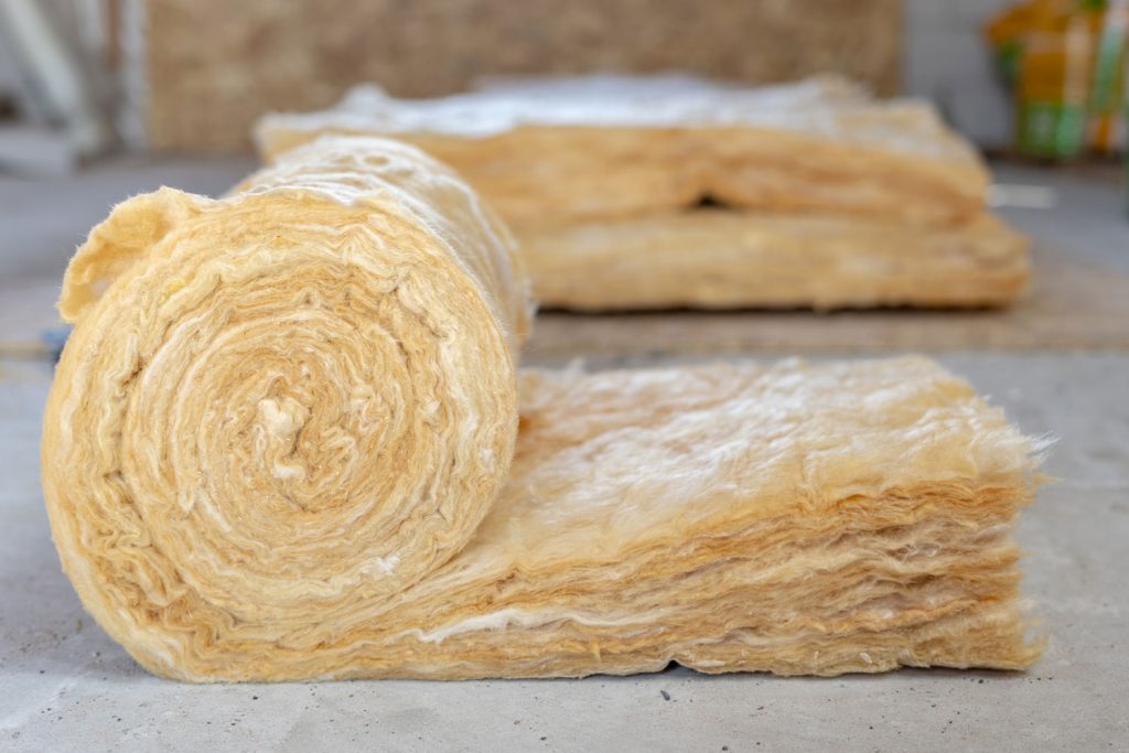 House insulation concept. Roll with mineral rockwool lying on attic floor inside house under construction
