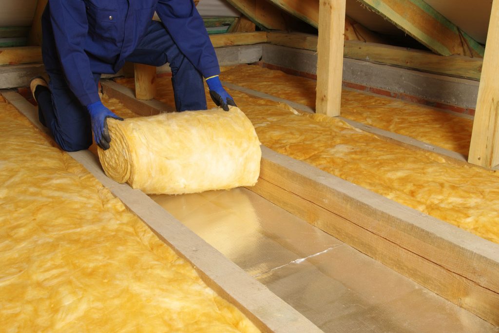 Installing the fiberglass insulation in the roof attic
