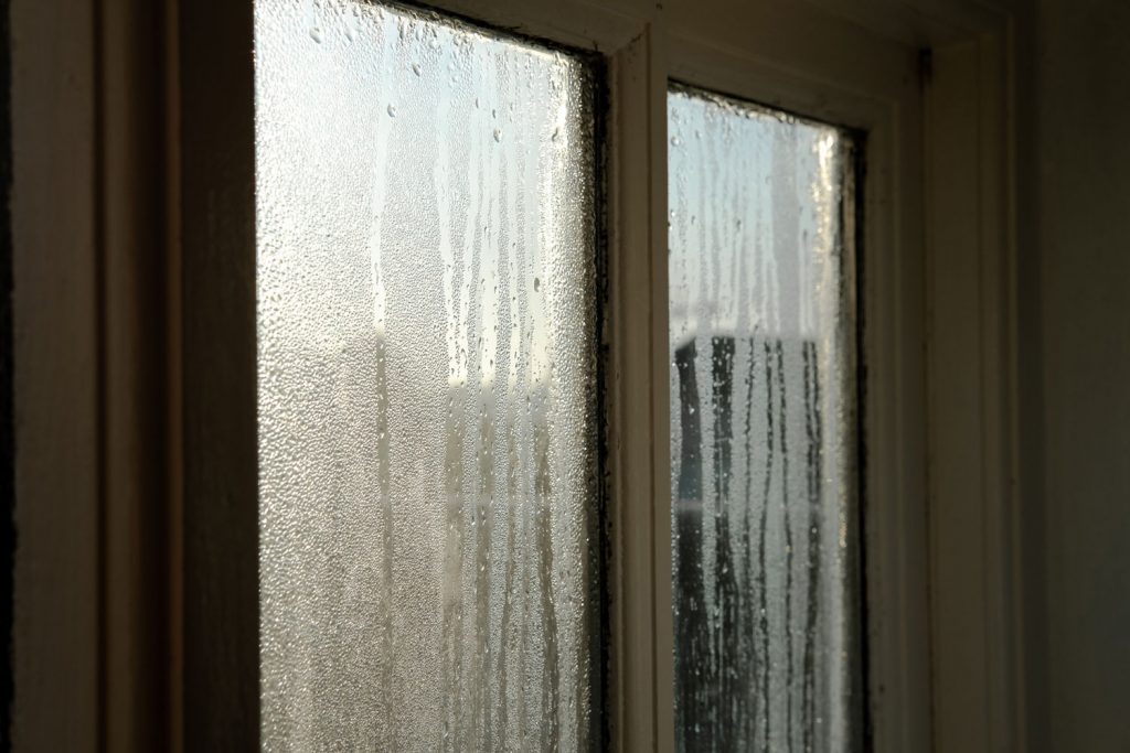 Taken during dawn, water is seen streaking down the glass with a dark surround and interior.