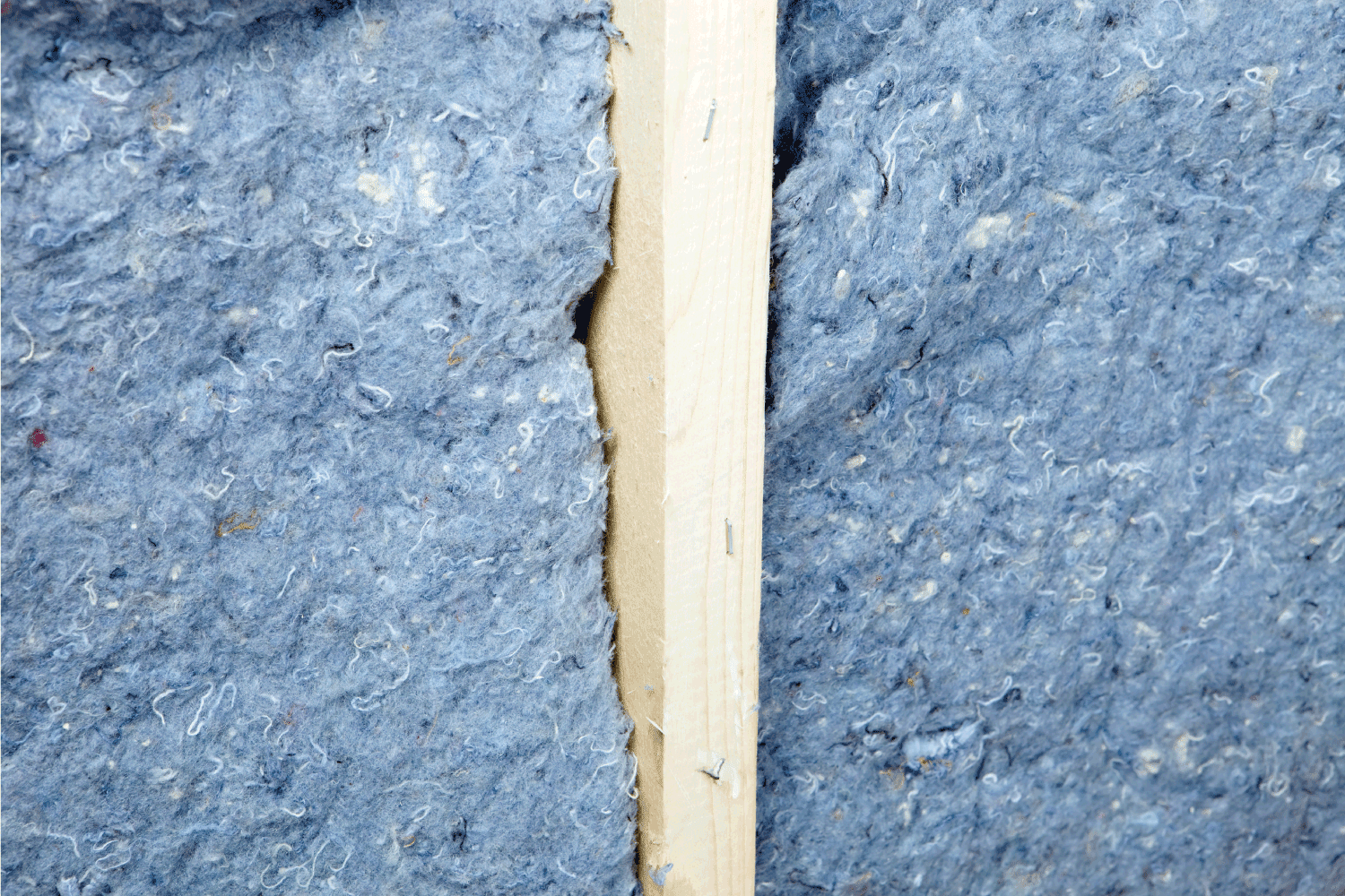 Two pieces of recycled blue jean denim insulation separated by a wall stud