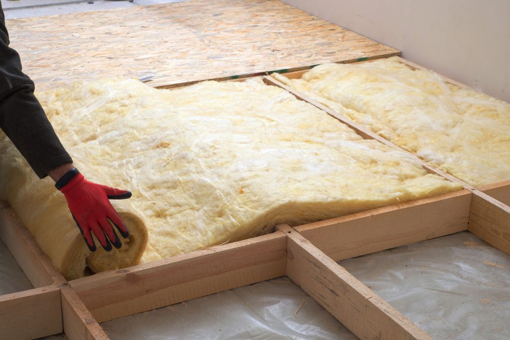 Worker laying out mineral wool in the attic of the house
