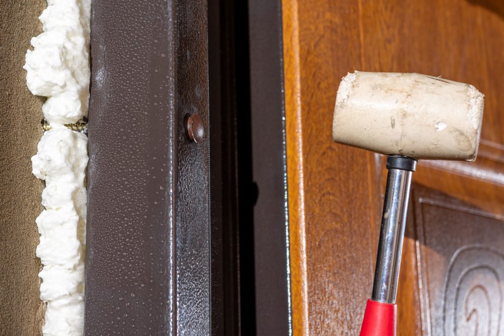 Worker using a soft mallet in mounting a door frame