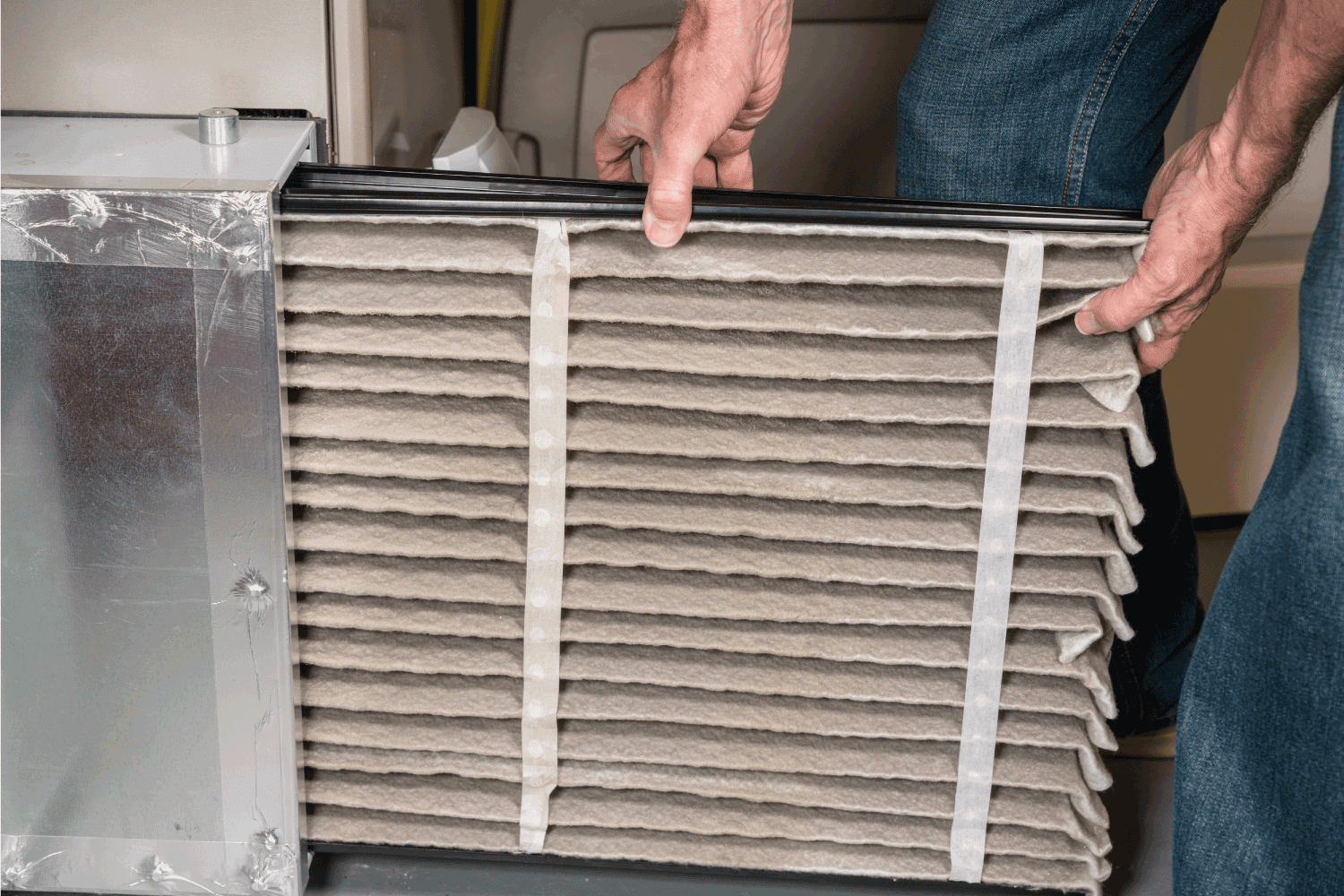 man changing a dirty air filter in a HVAC Furnace 