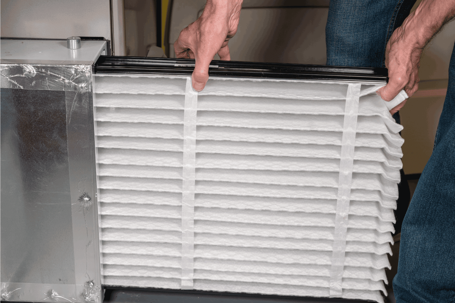 man inserting a new air filter in a HVAC Furnace
