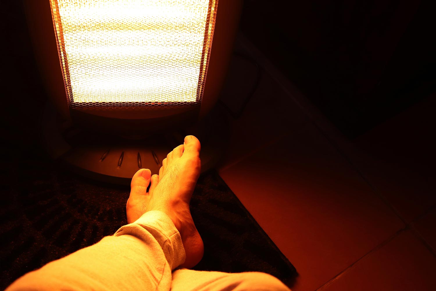 A Caucasian man's legs in front of an electric heater