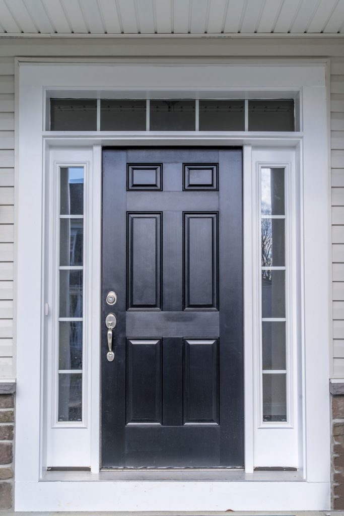 A black door with white trims and window panels on the sides