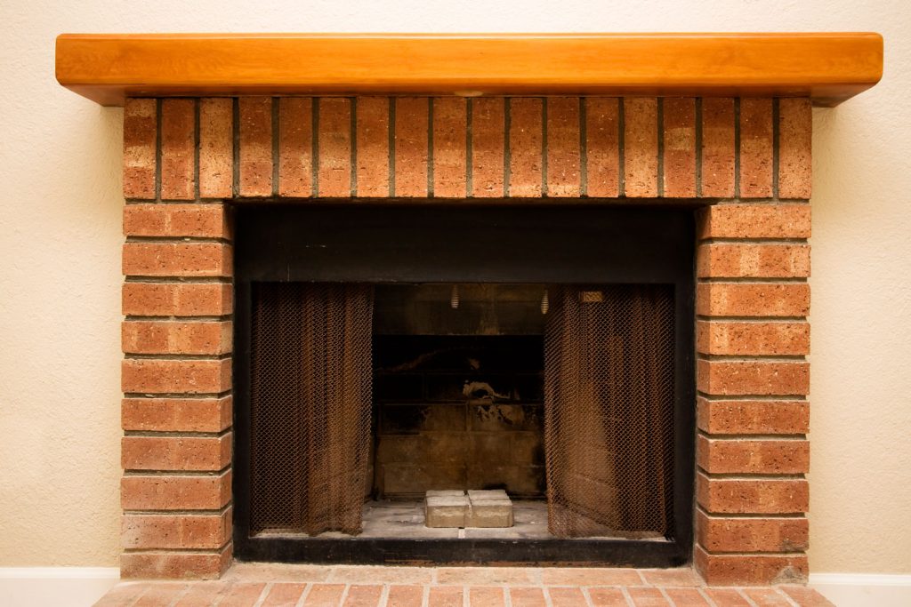 A brick fireplace with a wooden top mantel