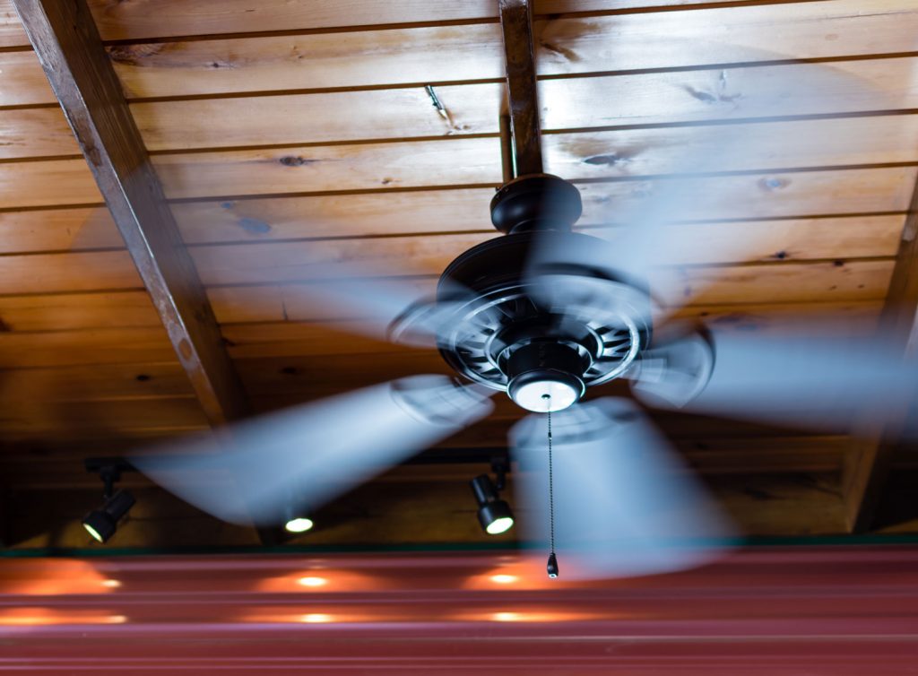 A ceiling fan shows motion blur as its blades spin around.