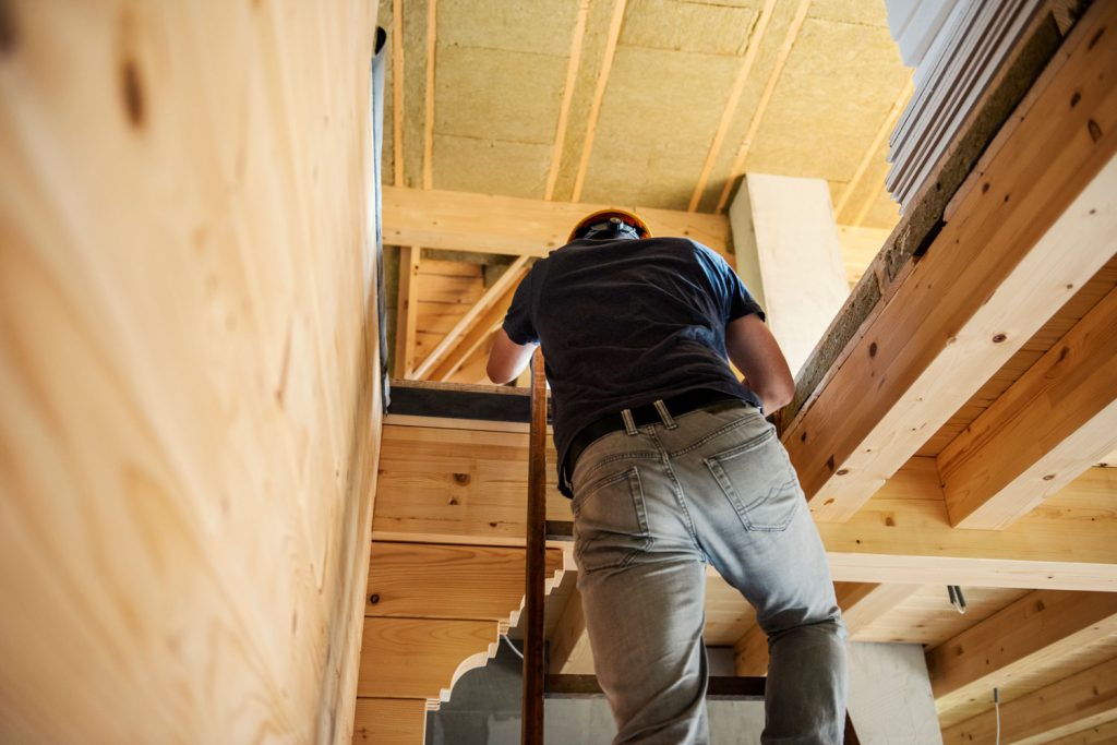 A construction worker checking the attic for insulation