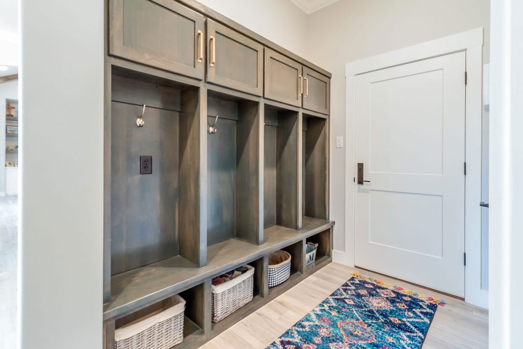 A dark gray four door cabinet with white trims and white walls with baskets underneath the cabinets