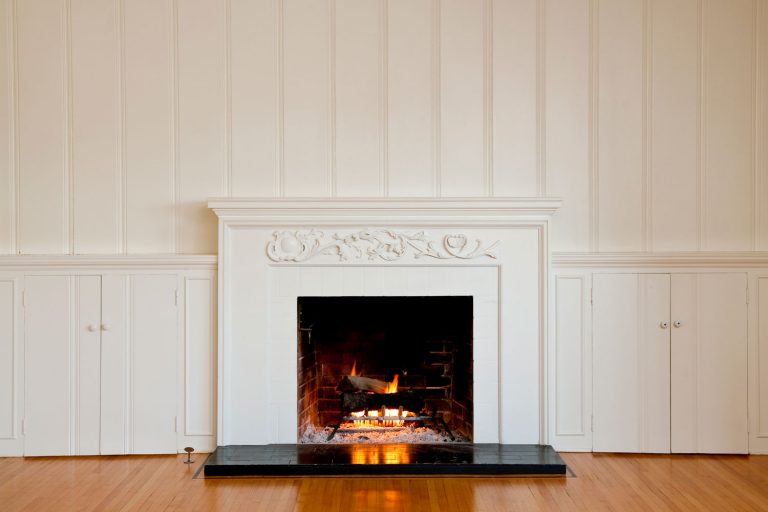 A fireplace with white mantel and white panel walls, How Big Is A Fireplace? [Dimensions Explored]