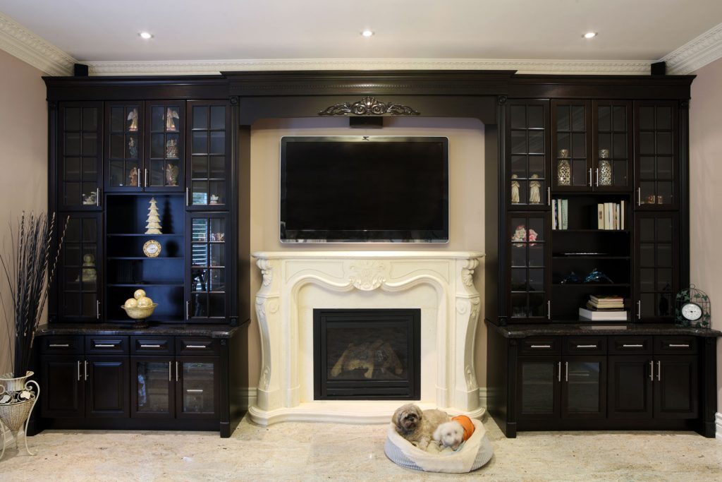 A gorgeous entertainment are with black cabinets and white mantel fireplace with a TV on top