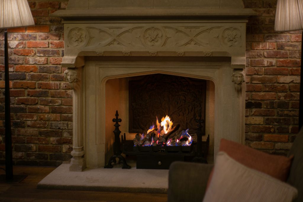 A gorgeous limestone fireplace mantel with burning firewood