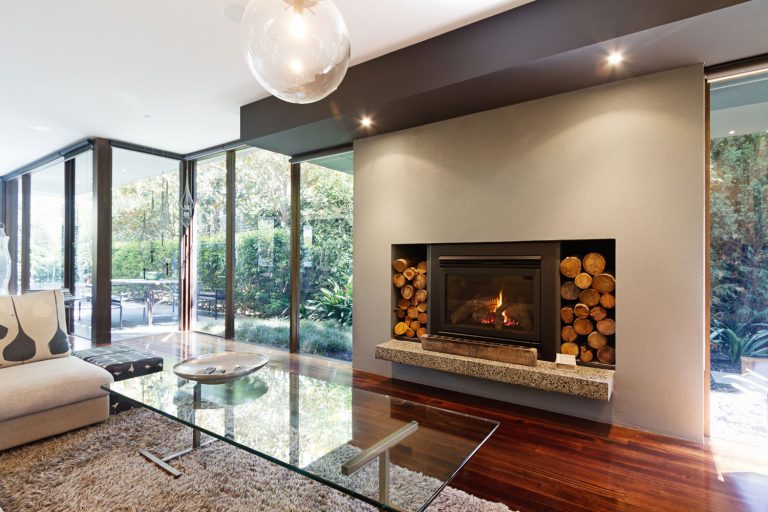 A gorgeous modern fireplace with logs on the side of an architectural designed wall for a gas fireplace, How Long Can A Gas Fireplace Stay On?