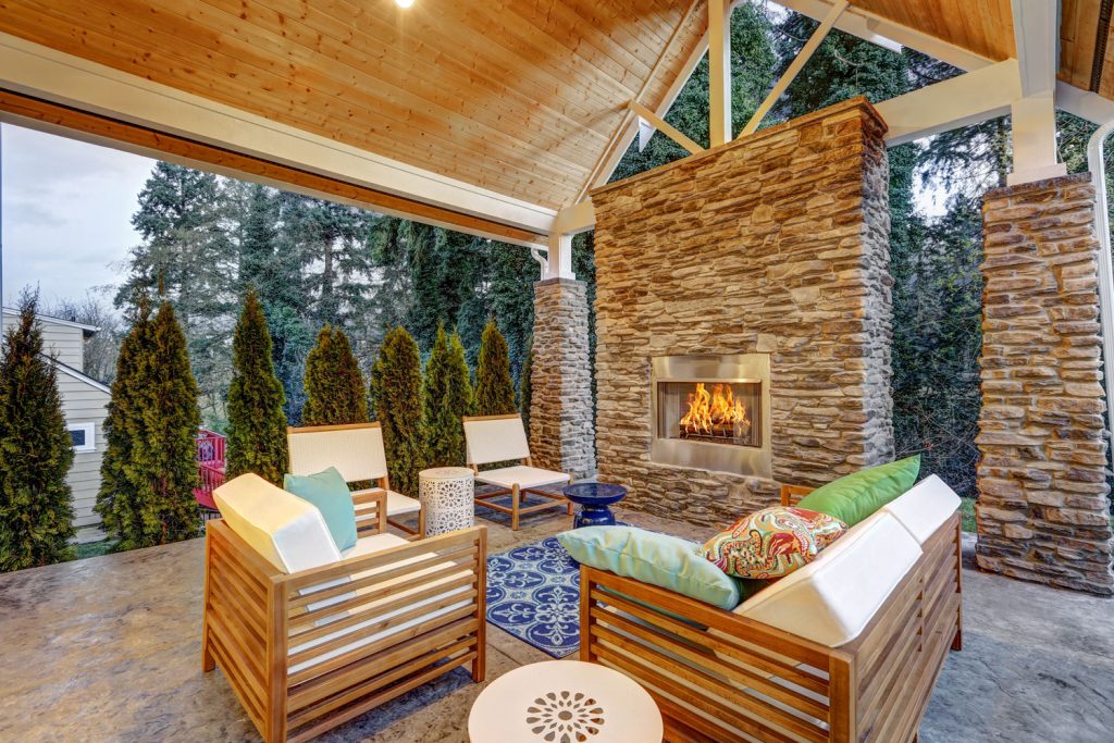 A gorgeous patio chic covered patio with decorative stone wall on the gas fireplace