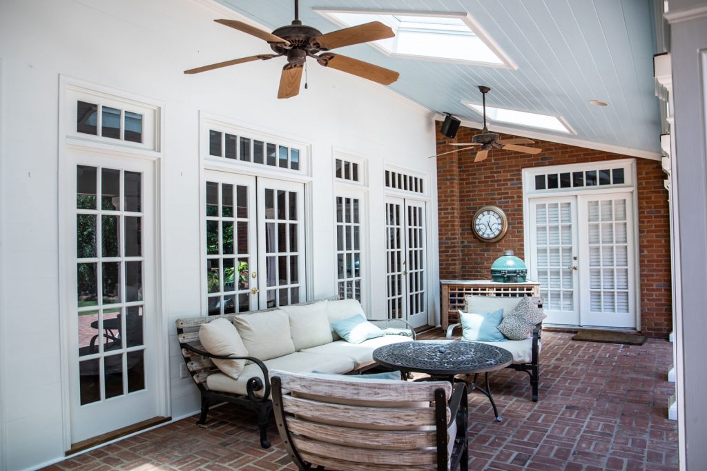 A gorgeous sealed patio with white painted doors and brick walls