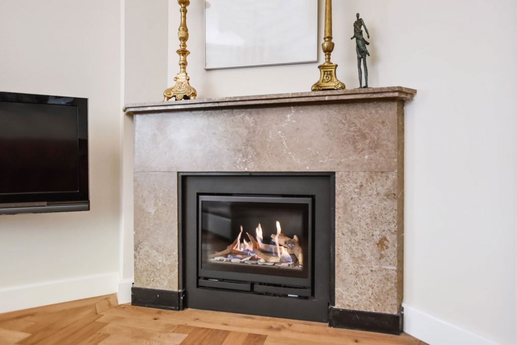 A luxurious stone covered fireplace mantel with a glass covered fireplace