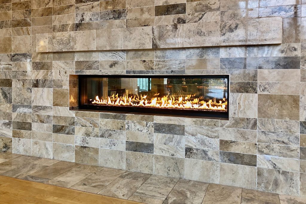 A panoramic gas fireplace in a stone tile wall cladding