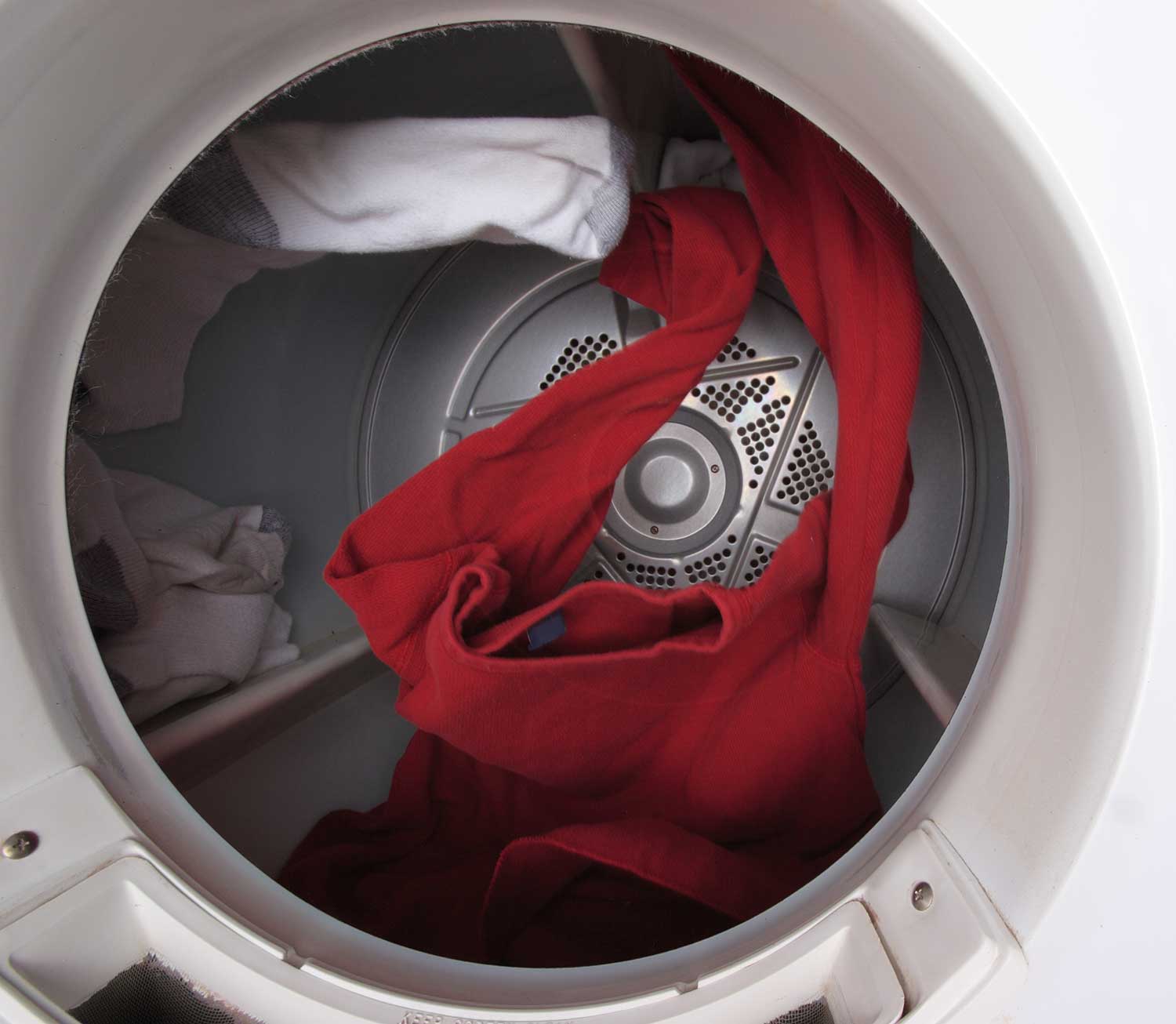 A red shirt and several socks tumble through the air inside a dryer