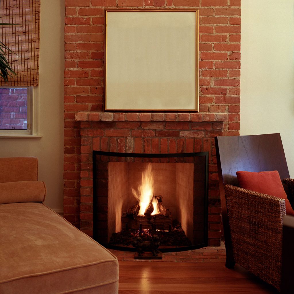 A tall brick fireplace with log burning for heat in the living room