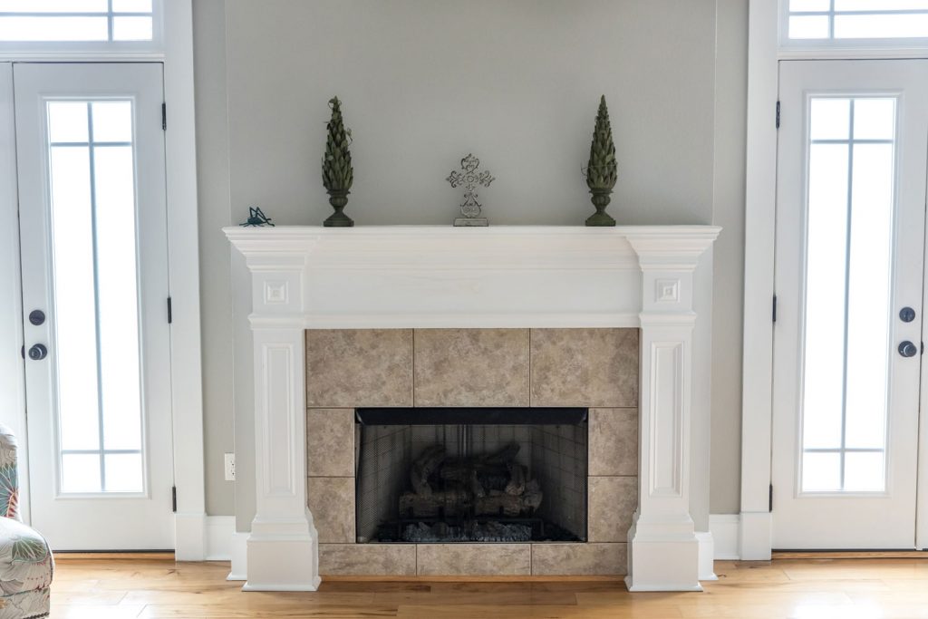 A white fireplace mantel with a screen for the fireplace
