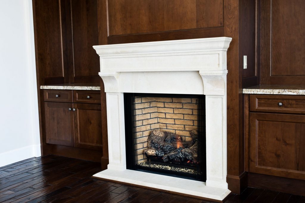A white mantel fireplace with wooden cabinets on the back