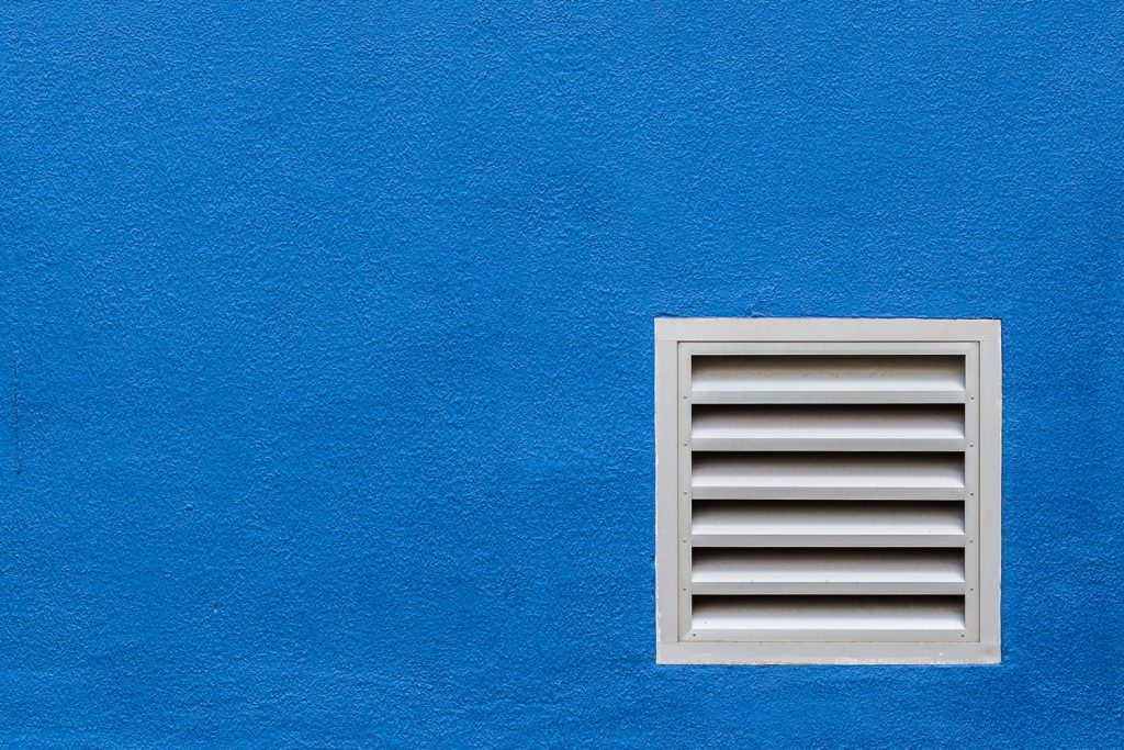 A white side vent on a blue wall