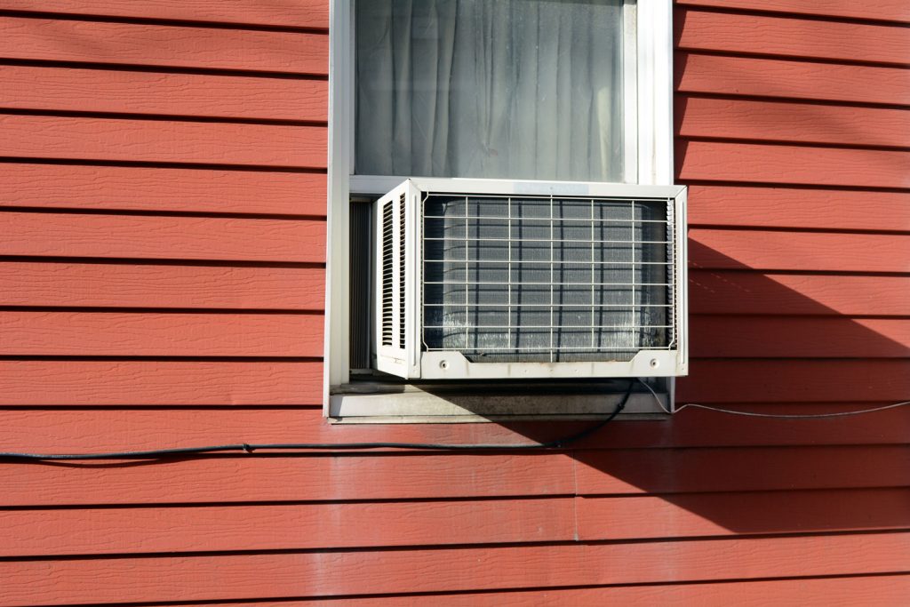 A window air conditioner for the living room with red wooden sidings
