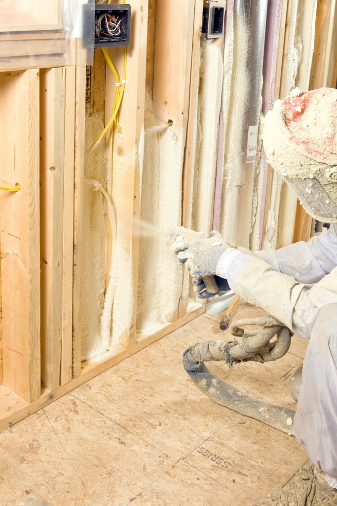 An insulation specialist applying foam insulation on the wall