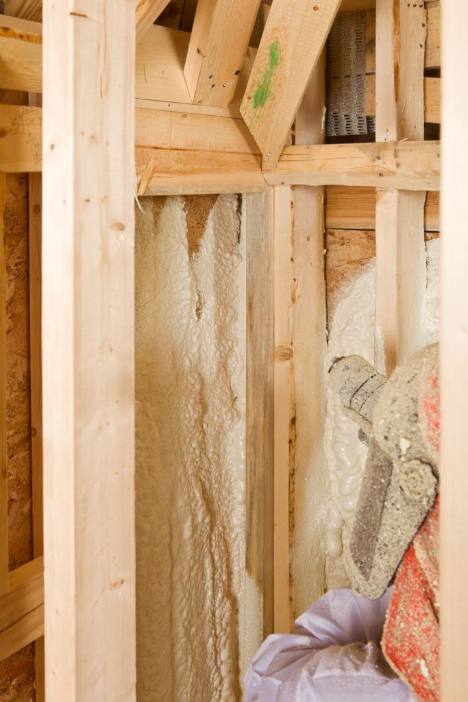 Applying foam insulation on the wooden framing