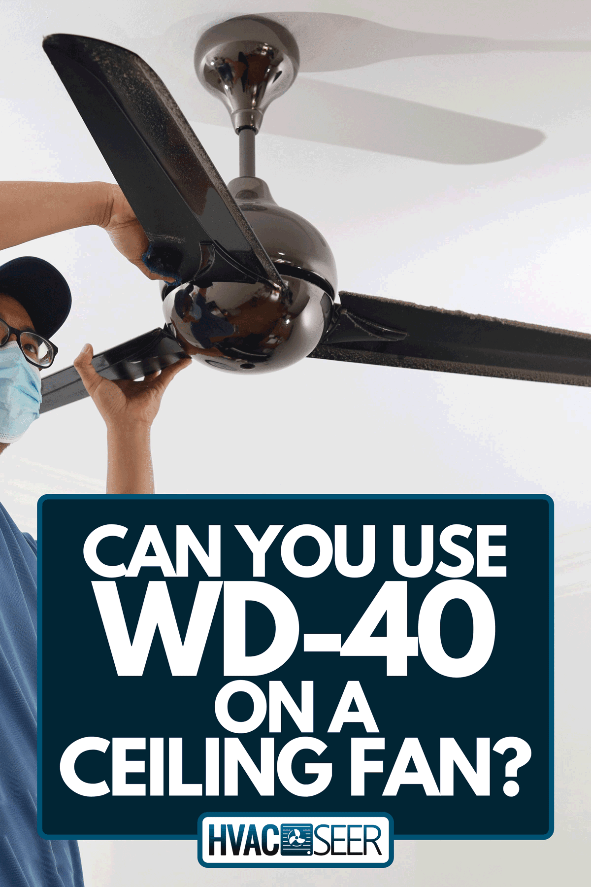 A man with a protective mask cleaning a ceiling fan, Can You Use WD-40 On A Ceiling Fan?