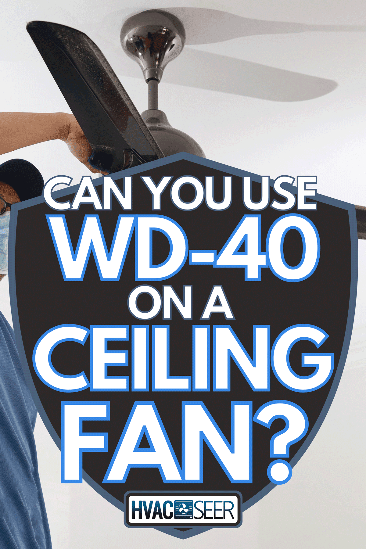A man with a protective mask cleaning a ceiling fan, Can You Use WD-40 On A Ceiling Fan?