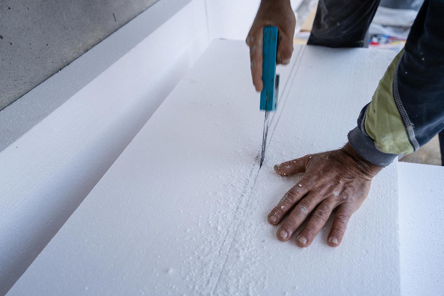Construction worker using the hand saw to cut the styrofoam insulation panel table