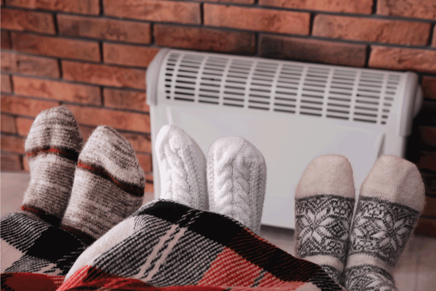 Family warming feet near electric heater at home