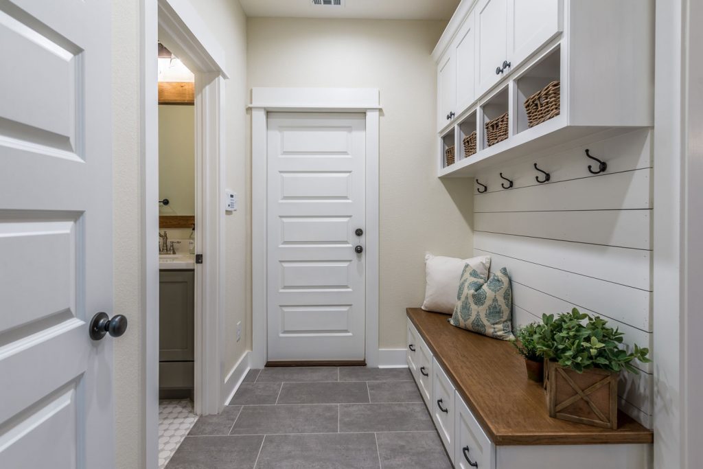 Interior of a beige colored mudroom with a wooden nook and drawers underneath