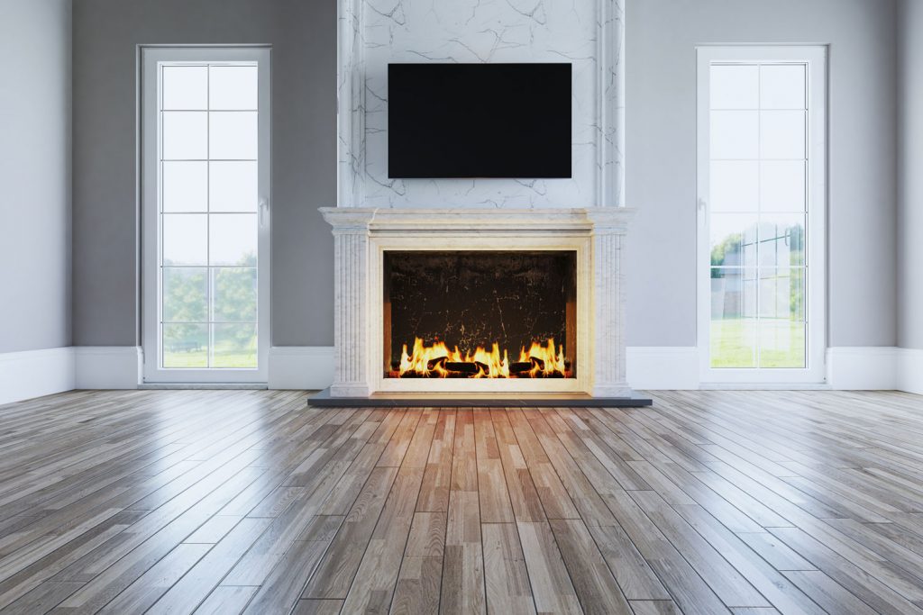Interior of an empty living room with wooden flooring, gray walls and white baseboard and a fireplace