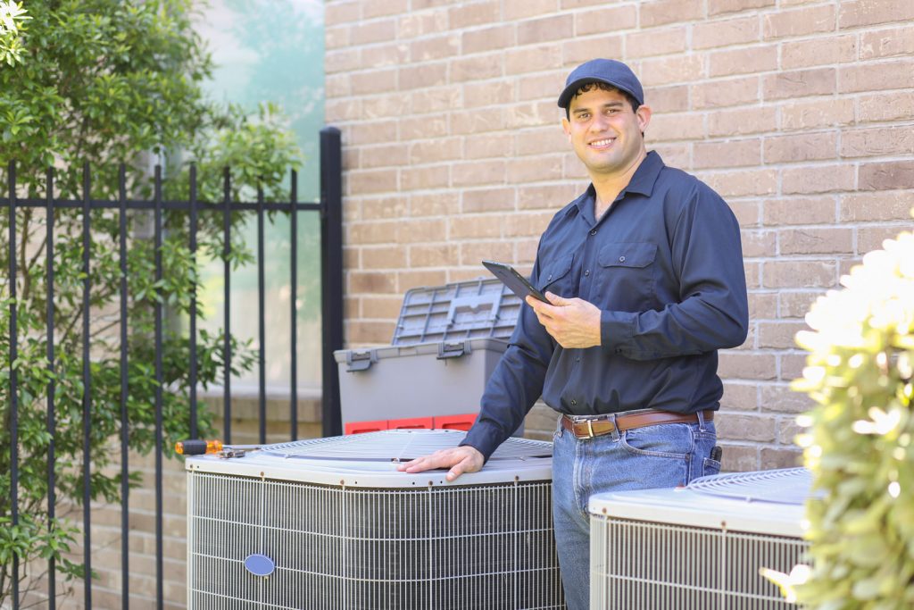 Latin descent, blue collar air conditioner repairman working at residential home