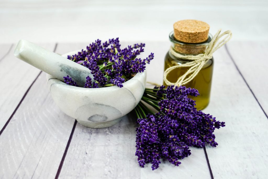 Mortar and pestel with lavander and a bottle filled with lavender oil