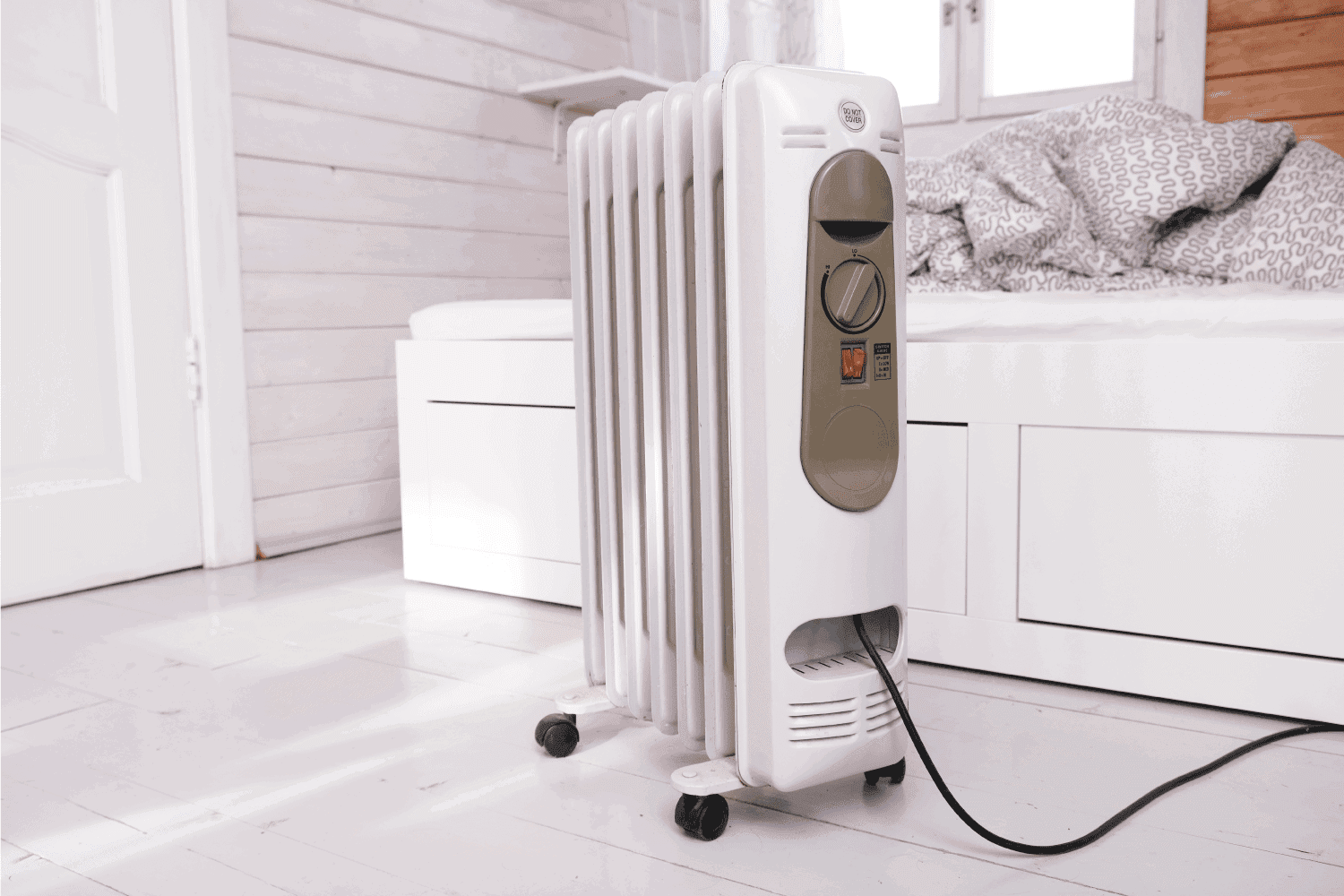 Oil-filled electrical mobile radiator heater for home heating and comfort control in the room in a wooden country house.