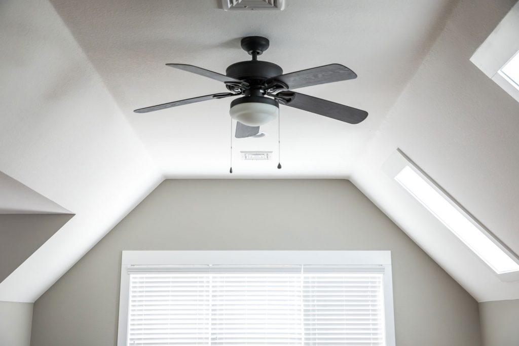Open and airy bonus room game room in a new construction house with a dark wood ceiling fan