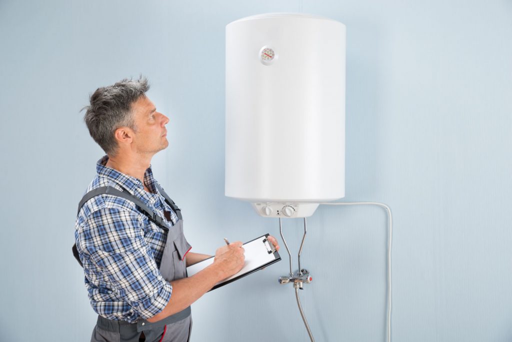 Portrait Of Mid-adult Male Plumber Holding Clipboard Looking At Electric Boiler
