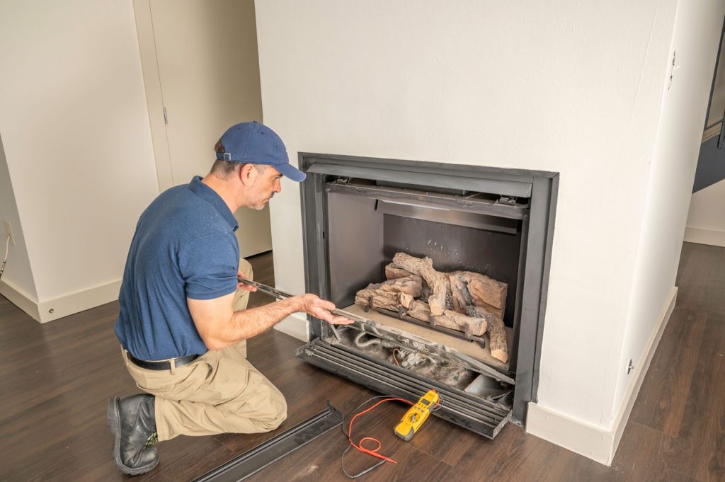 Service technician repairing a gas fireplace in a home
