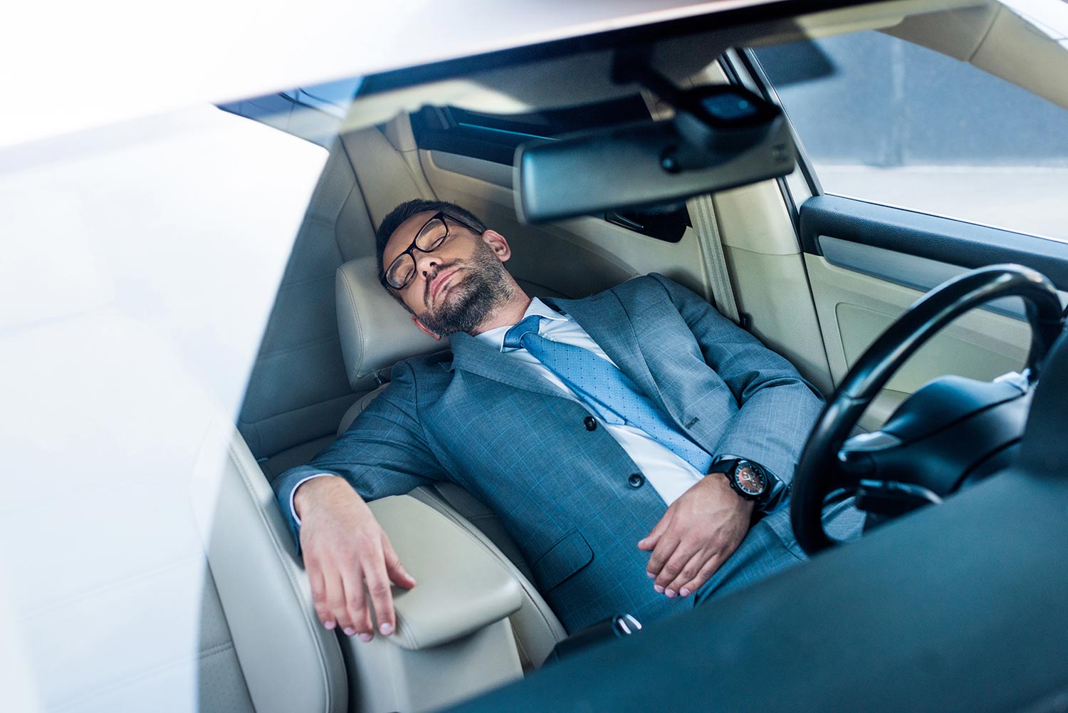 Tired businessman in eyeglasses sleeping in car