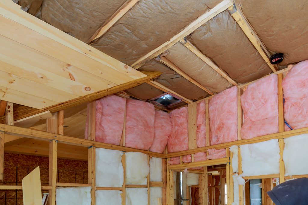 Undergoing work in a house with visible fiberglass insulation between wooden framing