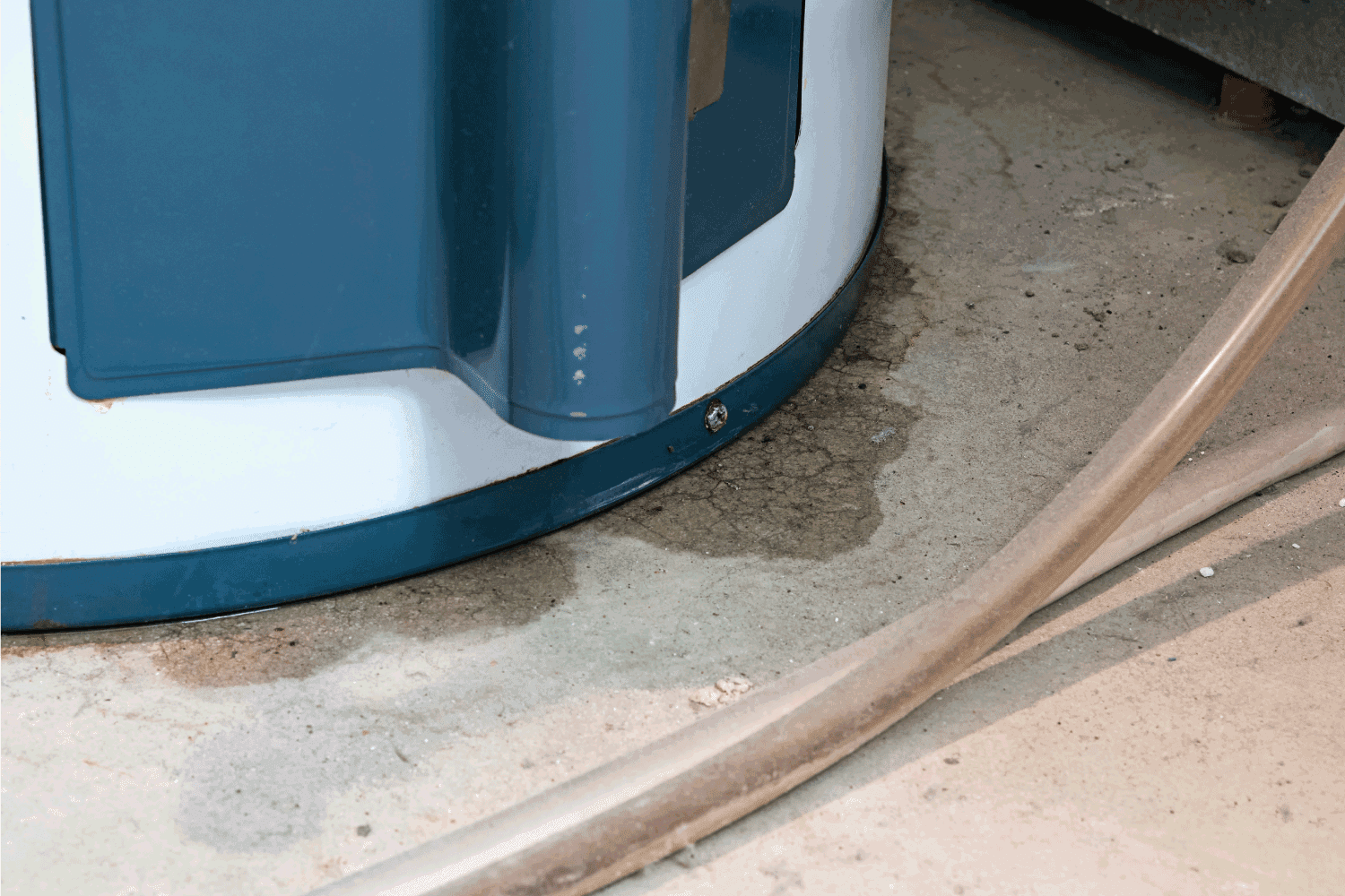 Water underneath a water heater shows the beginning of a leak, also shown by the signs of rust around the bottom rim