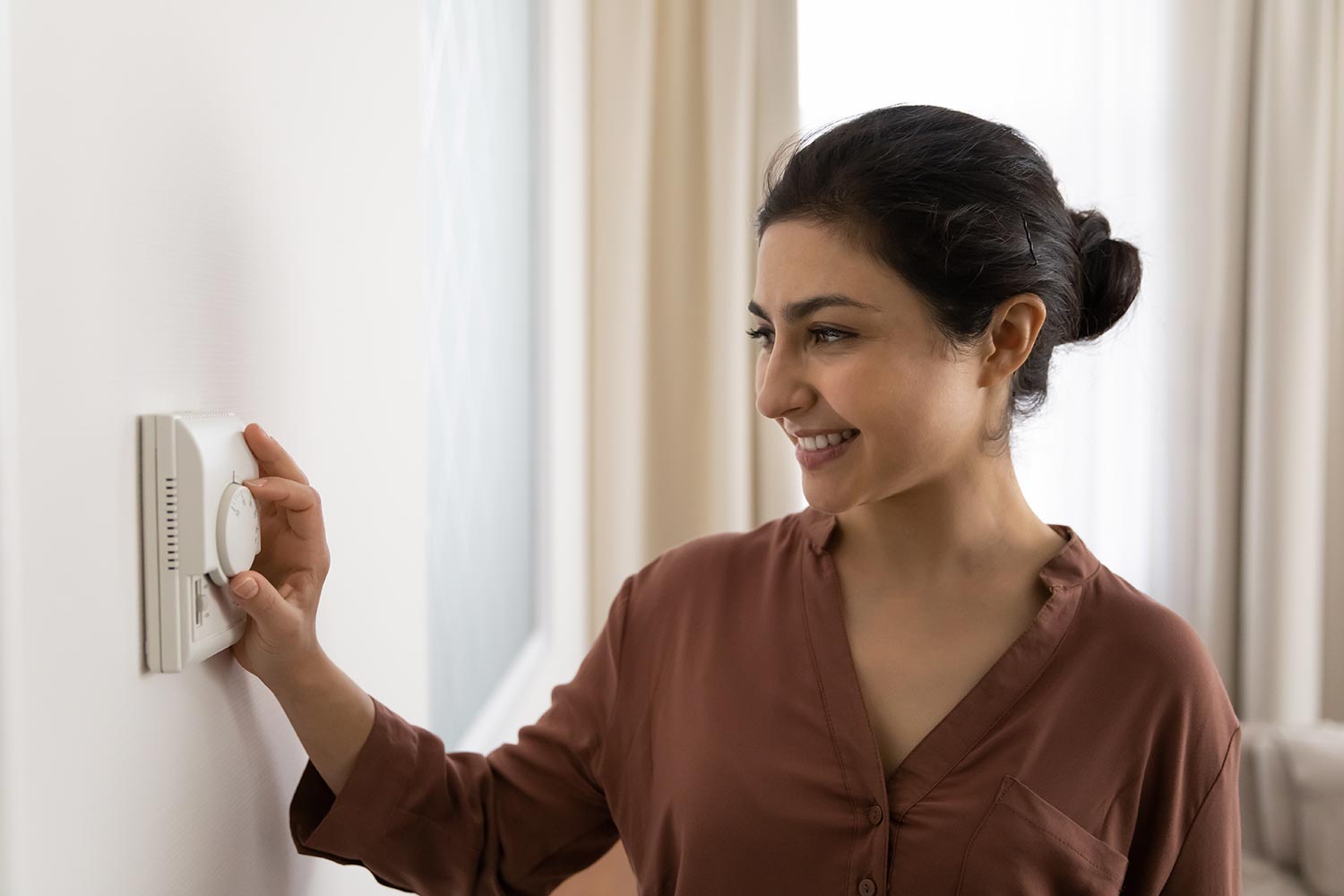 Woman setting comfortable domestic temperature using modern technology controller