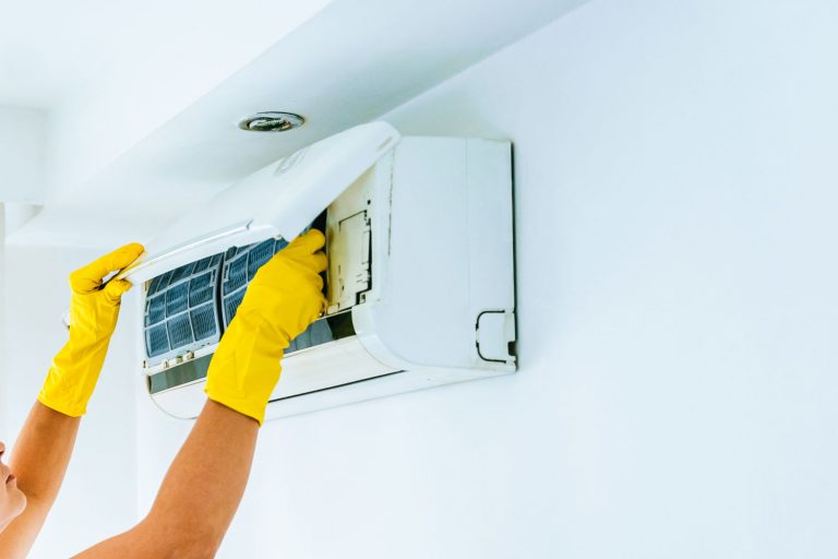 Woman wearing yellow gloves replacing the air filter of the air conditioning unit, How To Reset The Filter On A GE Air Conditioner?