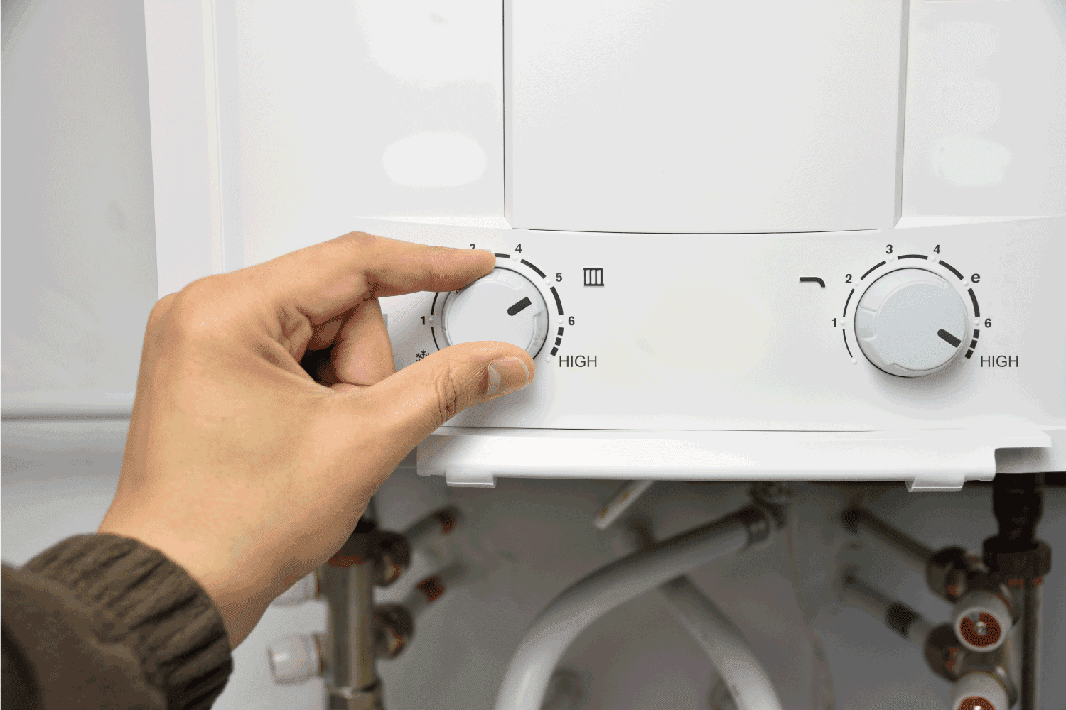 hand turning knobs of water heater at home