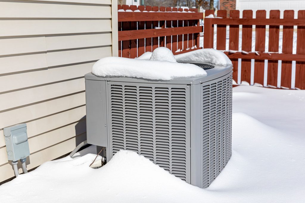 A gray air conditioning covered in snow