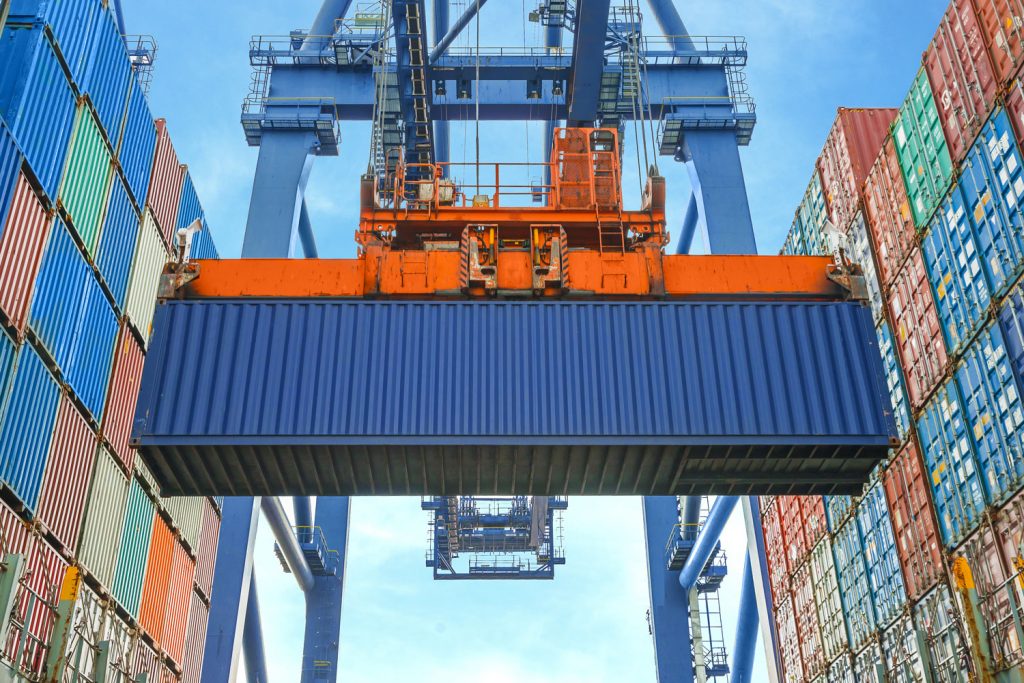 A huge crane lifting a blue colored shipping container